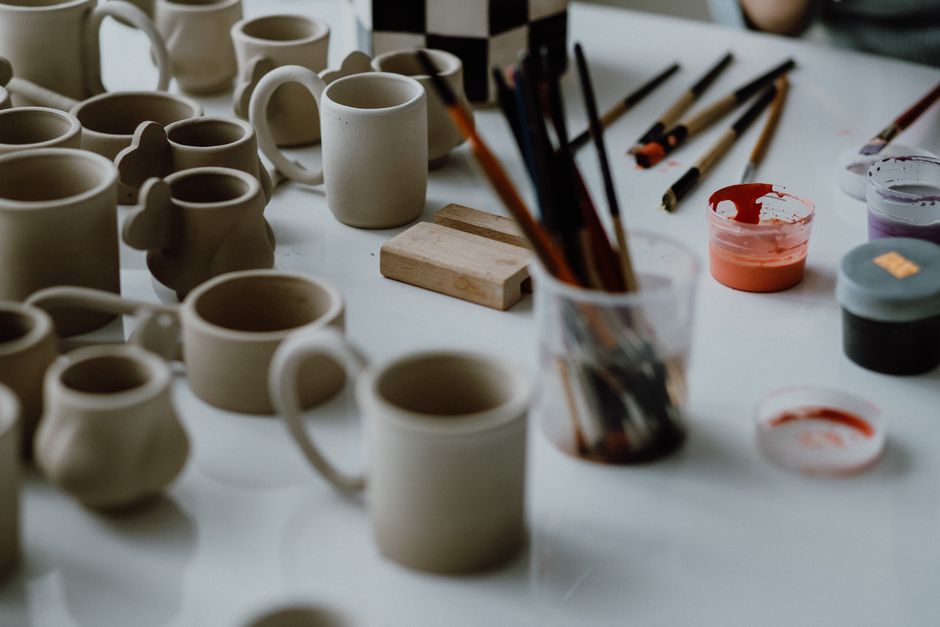 Unglazed mugs and brushes on the bench