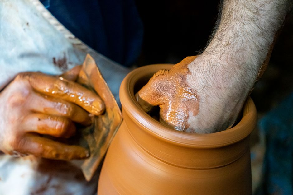 Hands trimming a terracotta pot on the wheel